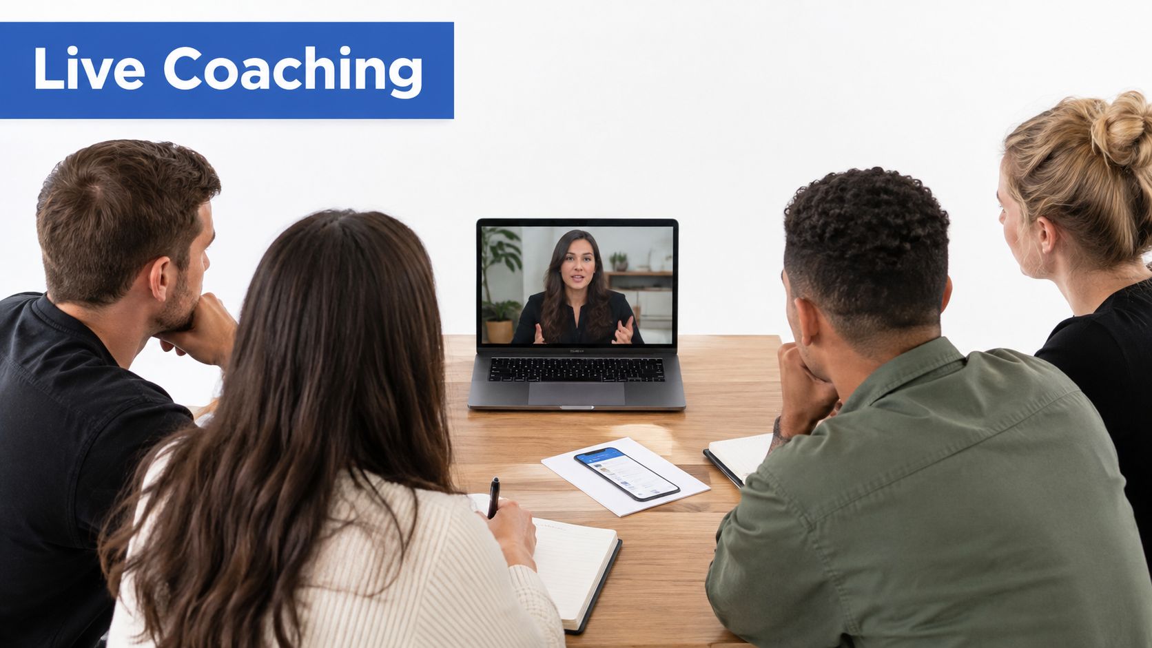 A group of diverse people sitting at a wooden table participating in an online live coaching session.