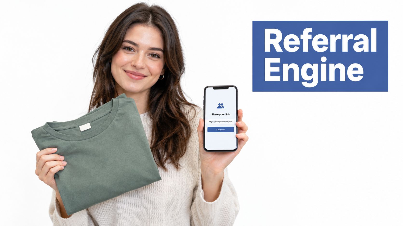 A smiling woman holding a green folded shirt and showing a referral link on her smartphone screen.